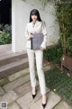 A woman in a white suit holding a book.