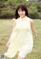 A woman in a yellow dress is walking in a field.