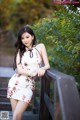 A woman in a white dress posing on a wooden bridge.