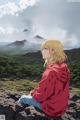 A girl sitting on top of a mountain looking out over a valley.