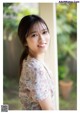 A woman in a floral shirt leaning against a wall.