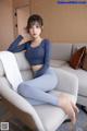 a woman sitting on top of a couch next to a pillow