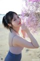 A woman holding a bunch of pink flowers on a beach.