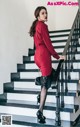 A woman in a red dress is standing on the stairs.