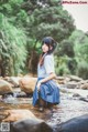 A woman in a school uniform is standing in a stream.