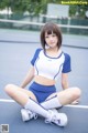 A woman sitting on a tennis court wearing a blue and white outfit.