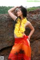 A woman in a hawaiian dress posing on a rock.