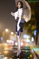 A woman standing in the rain holding an umbrella.