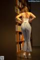 A woman standing in front of a bookshelf with her back to the camera.