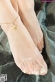 a woman wearing a gold anklet with a bird on it