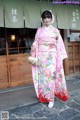 A woman in a pink kimono standing in front of a building.