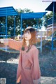 A woman standing in front of a playground with her arms outstretched.