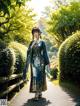 A woman in a blue kimono walking down a path in a park.