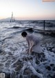 A woman in a white dress standing in the ocean.