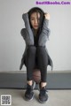 A woman sitting on a basketball with her hands on her head.