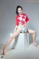 A woman sitting on top of a white box holding a soccer ball.