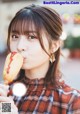 A young woman eating a hot dog on a stick.