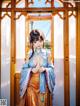 A woman in a blue and orange kimono standing in front of a window.