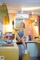 A woman sitting on top of a stool in a kitchen.