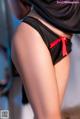 A woman in a black top and black panties with a red bow.