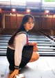 A woman in a school uniform crouching on the floor.