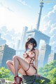 A woman in a bikini sitting on a rock in front of a city.