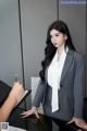 A woman in a business suit sitting at a desk.