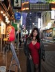 A woman in a red dress standing in the middle of a street.