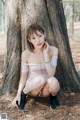 A woman sitting on the ground next to a tree.