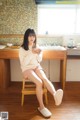 A woman sitting on a stool in a kitchen.