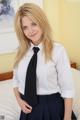 A woman in a white shirt and black tie posing on a bed.